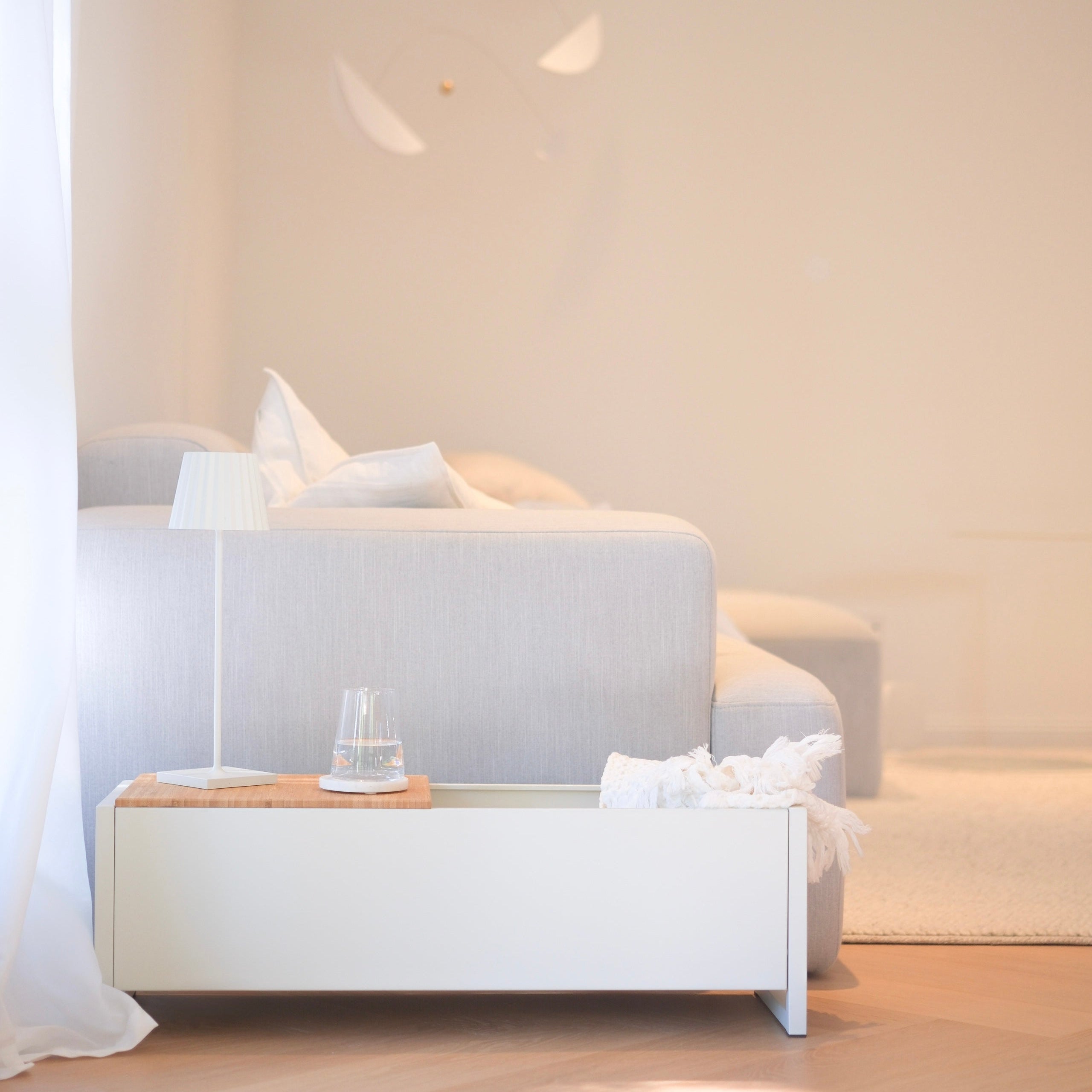 Plantbox Dublin in weiß neben Couch mit Decke, Wasserglas und Lampe Frontansicht