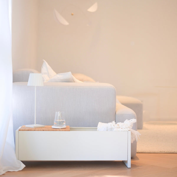 Plantbox Dublin in Weiß neben Couch mit Decke, Wasserglas und Lampe