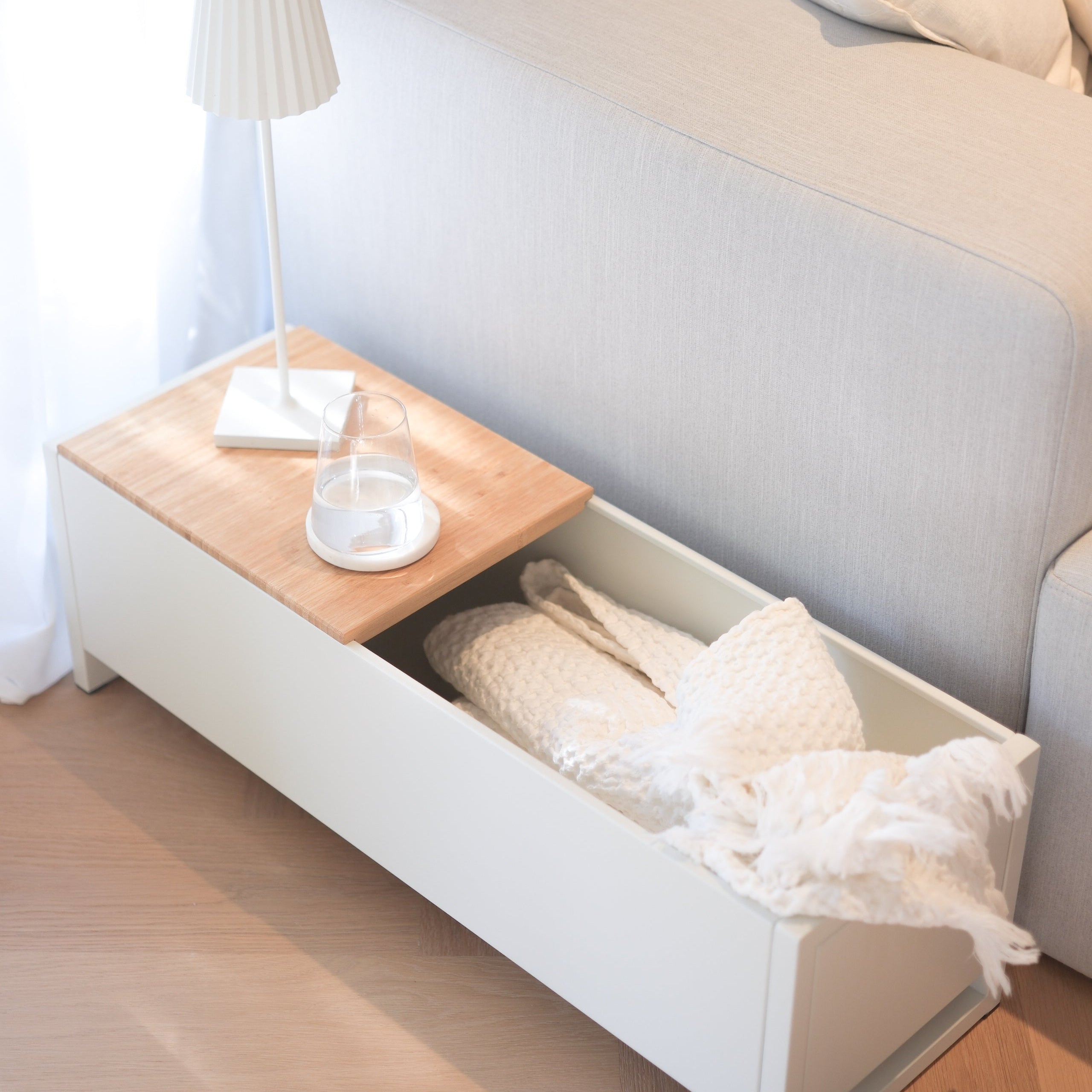 Plantbox Dublin in weiß Seitenansicht mit Decke, Wasserglas und Lampe neben Couch